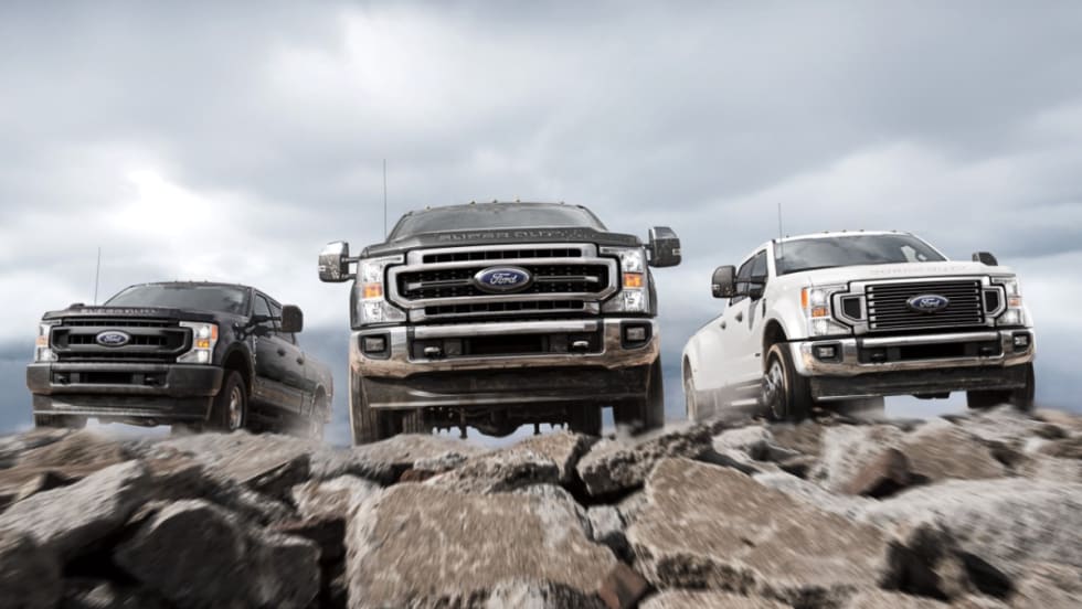 Various 2021-2022 Ford Super Duty driving on rocks towards the camera.