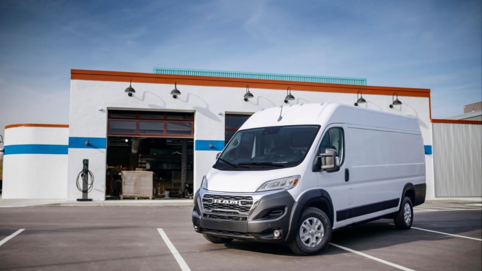 Front left side of a 2025 Ram ProMaster EV parked in front of a auto shop.
