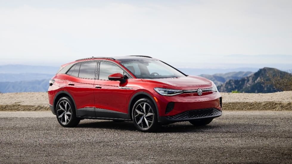 A red 2025 Volkswagen ID.4 parked on a road overlooking mountains.