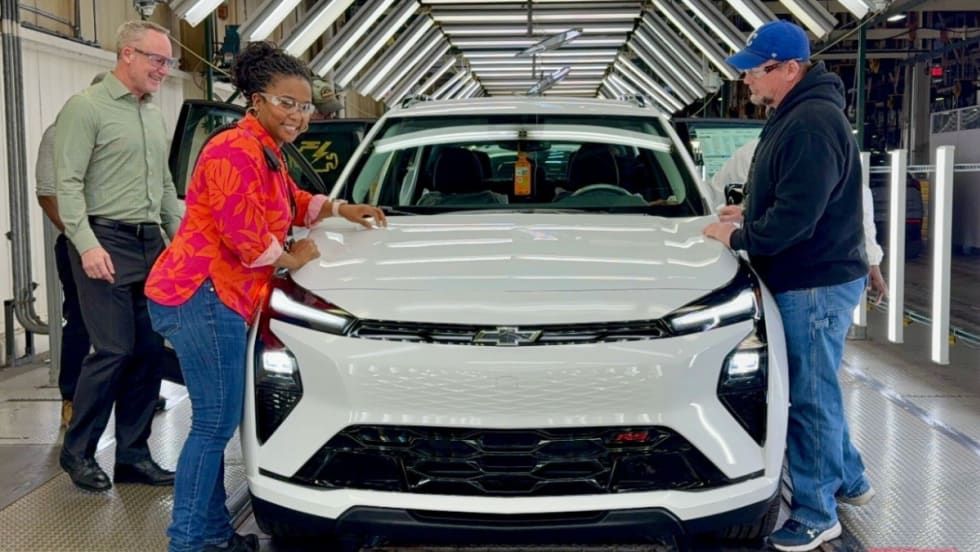 Three people stand next to a Chevy Equinox.