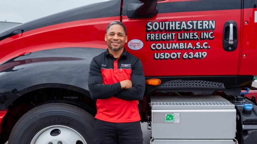 Photo of smiling truck driver Harold Perry with arms crossed in front of Southeastern Freight Lines truck