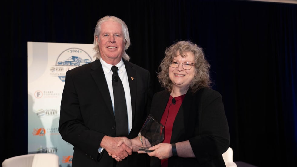 Man in suit receiving award from woman on stage