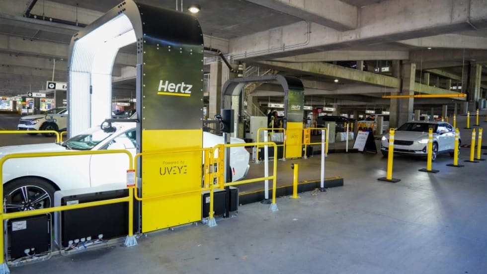 A vehicle inspection arch-style imaging structure that takes photos of rental cars returning to an airport parking deck.