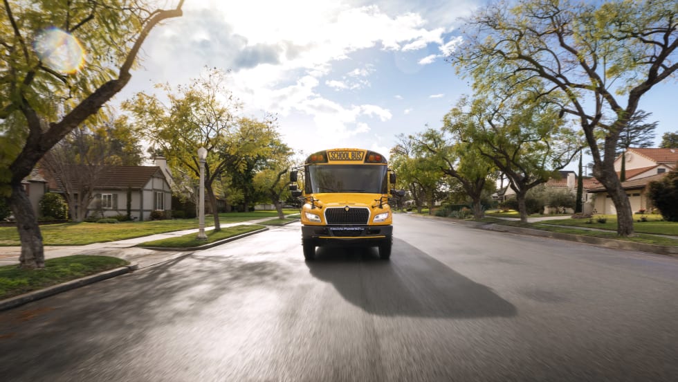 Front view of an IC Bus next generation electric CE Series bus driving on a suburban street.