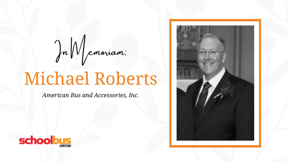 a black and white photo of michael roberts against a white flowery background with text that says "In memoriam Michael Roberts"