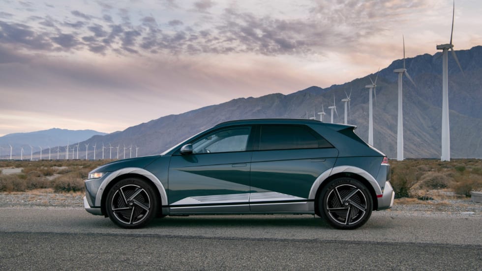 Hyundai IONIQ 5 electric SUV parked near wind turbines, named Best Compact Electric SUV, highlighting fast charging, modern design, and efficiency.
