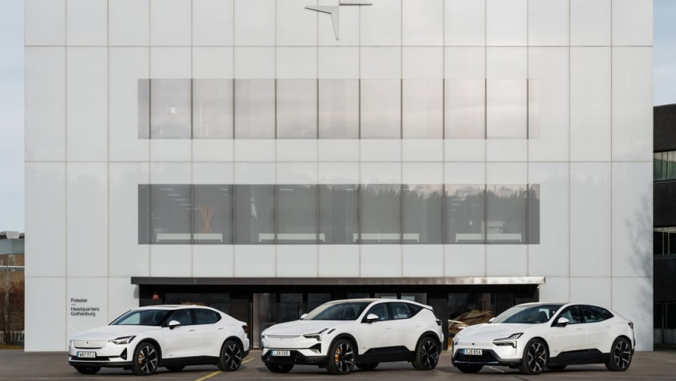 An image of three white Polestar cars lined up in front of a Polestar company building.