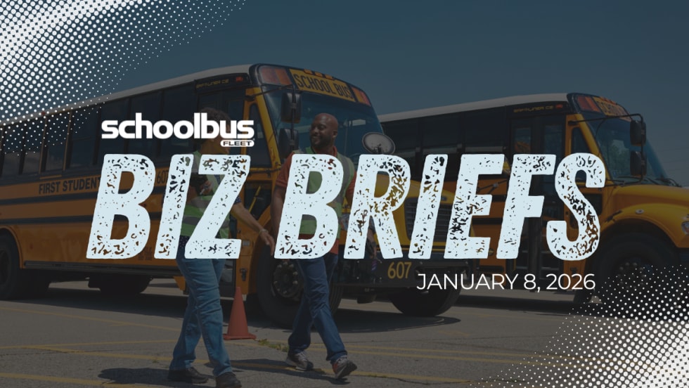 Image of two people in high visibility vest walking in front of parked school buses with text reading "Biz Briefs."