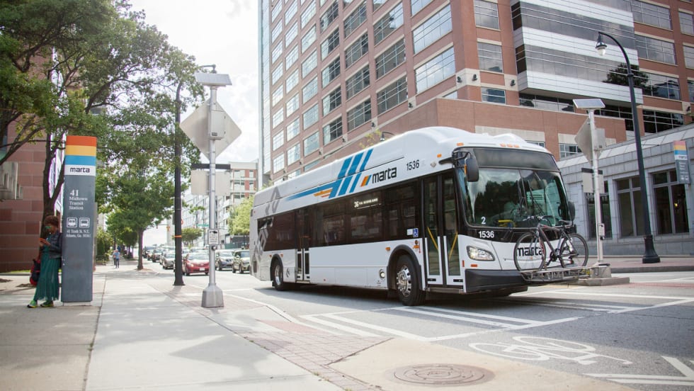A white MARTA public transit bus near a bus stop.