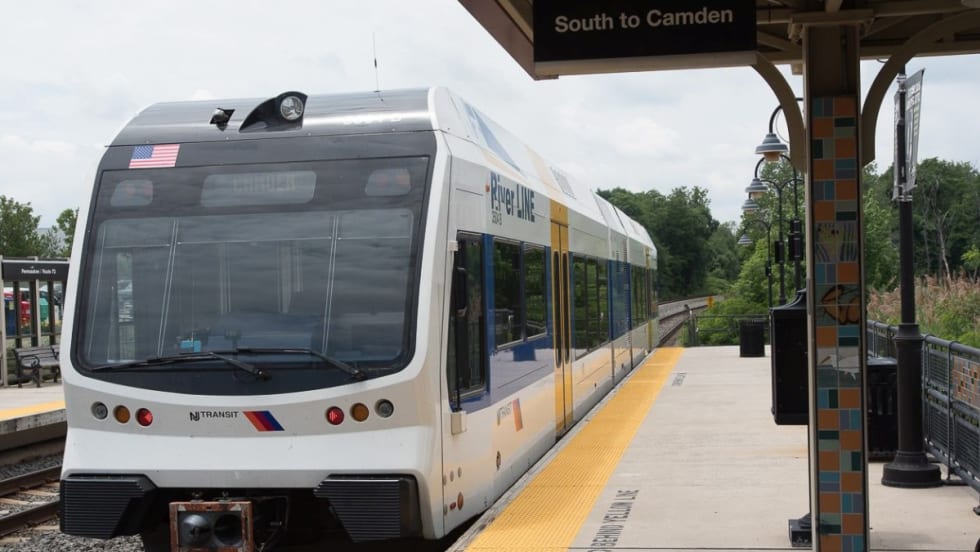 A white NJ TRANSIT River Line rail car at a station.