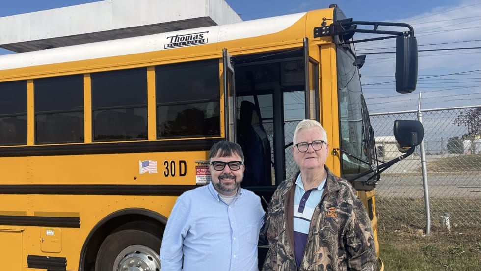 two men stand in front of a school bus in tennessee