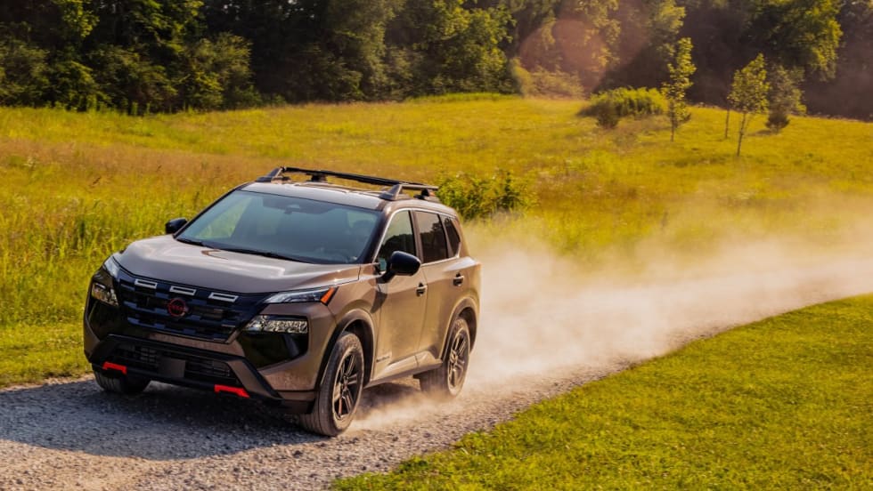 A tan SUV drives down a dirt road.