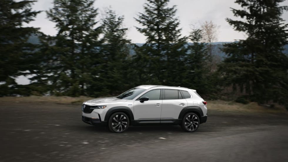A silver Mazda SUV being driven on a mountain road. 