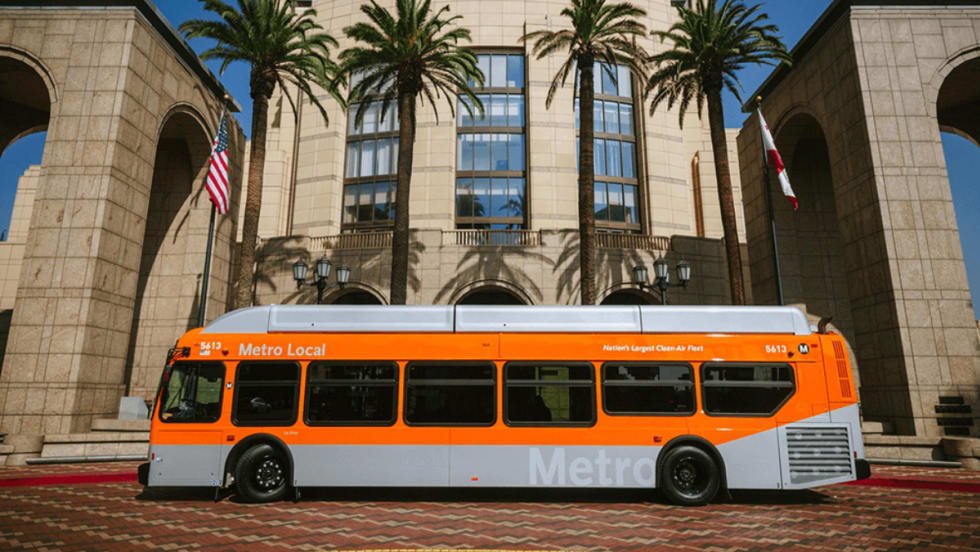 Side view of an orange LA Metro bus parked outside. 