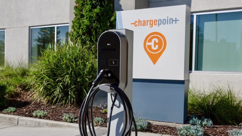 An outdoor LG electric vehicle charging station in front of a ChargePoint company sign and office building.