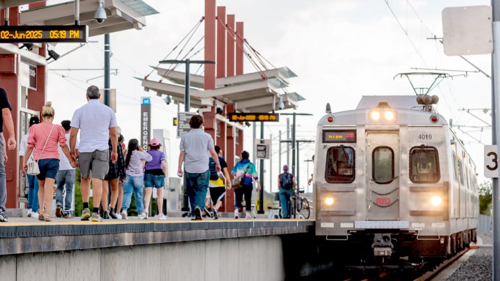 Riders walk down an outdoor rail line platform for the Regional Transportation District in Denver, Colorado.