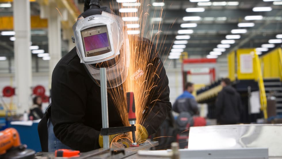 A worker cutting metal.