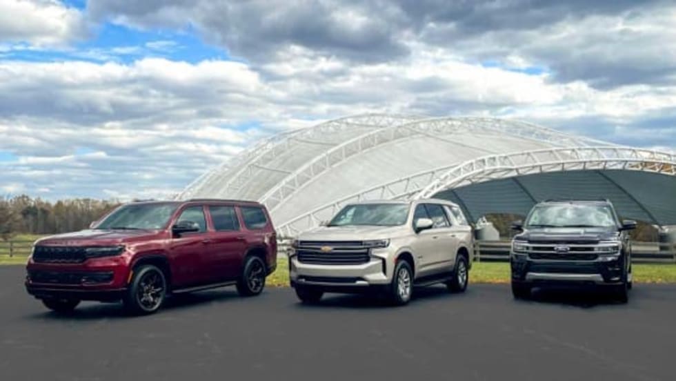 A lineup of large SUVs are shown. From left, those include a maroon Jeep Wagoneer, off-white Chevrolet Tahoe, and navy blue Ford Expedition.
