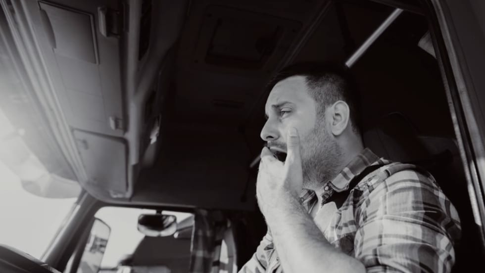 Truck driver yawning behind wheel