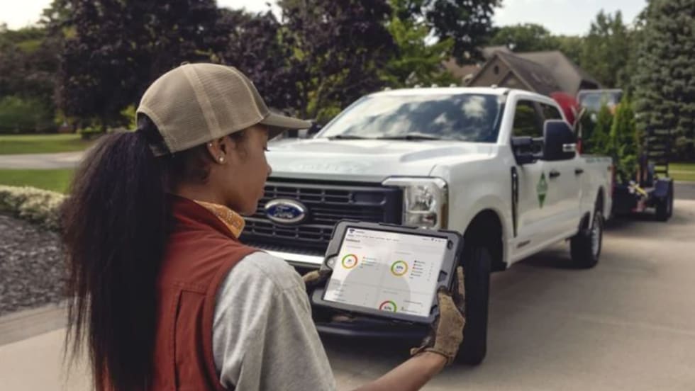 A worker using an ipad standing in front of a work truck.