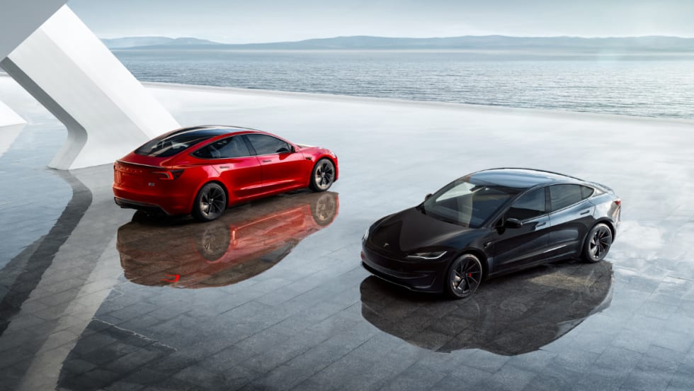 Two Tesla Model Y vehicles parked in front of a horizon. One is red and one is black.