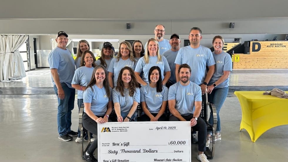 A group of people in matching light blue shirts pose with a check made out to Bree's Gift for $60,000.