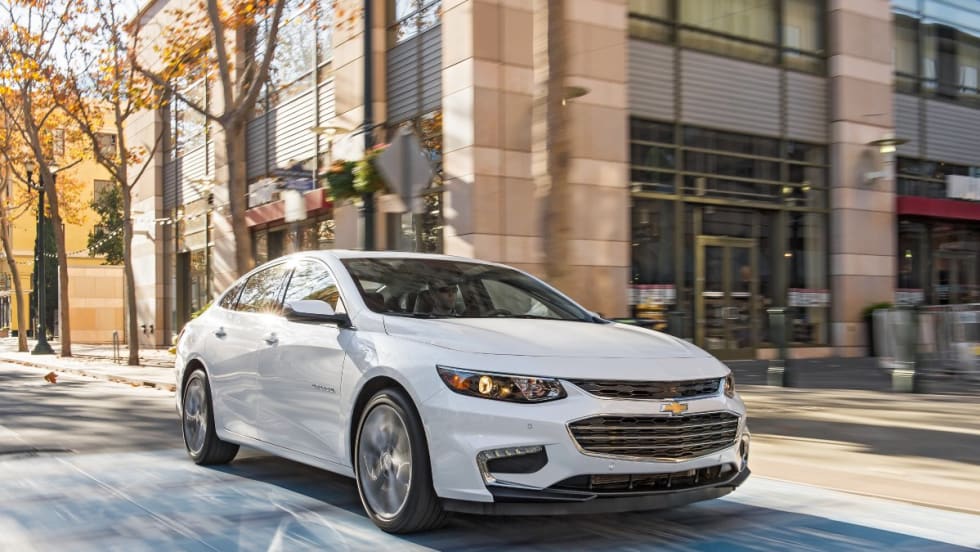 White Chevrolet Malibu driving through a city.