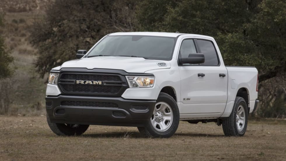 White RAM truck in front of foliage.