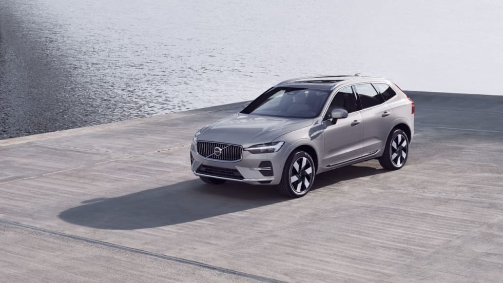 A silver SUV sits on a gray concrete surface with water in the background.