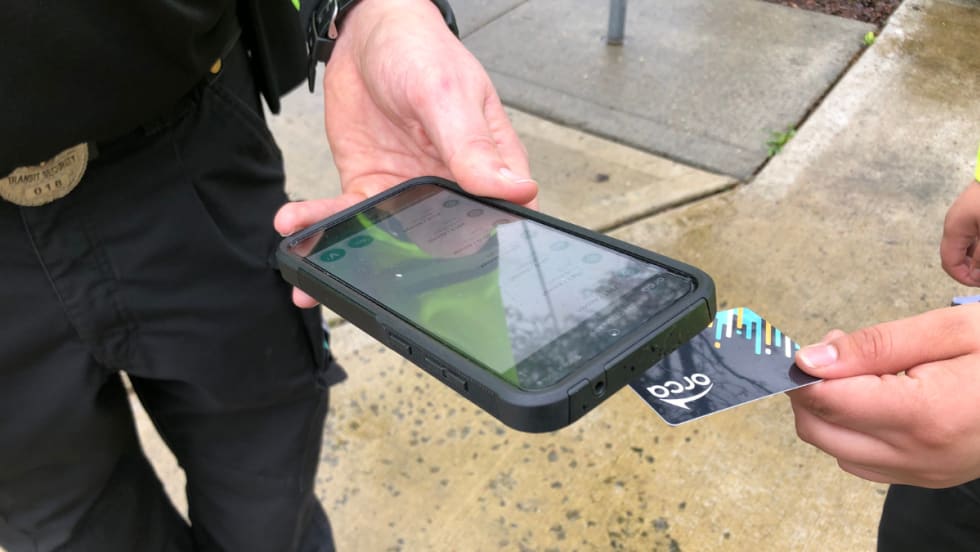 A rider tapping their ORCA card with a fare enforcement officer.