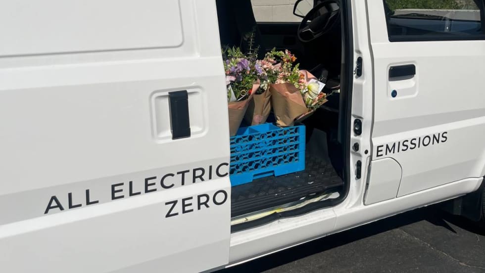 A Class 1 electric cargo van with door open shows flower deliveries.