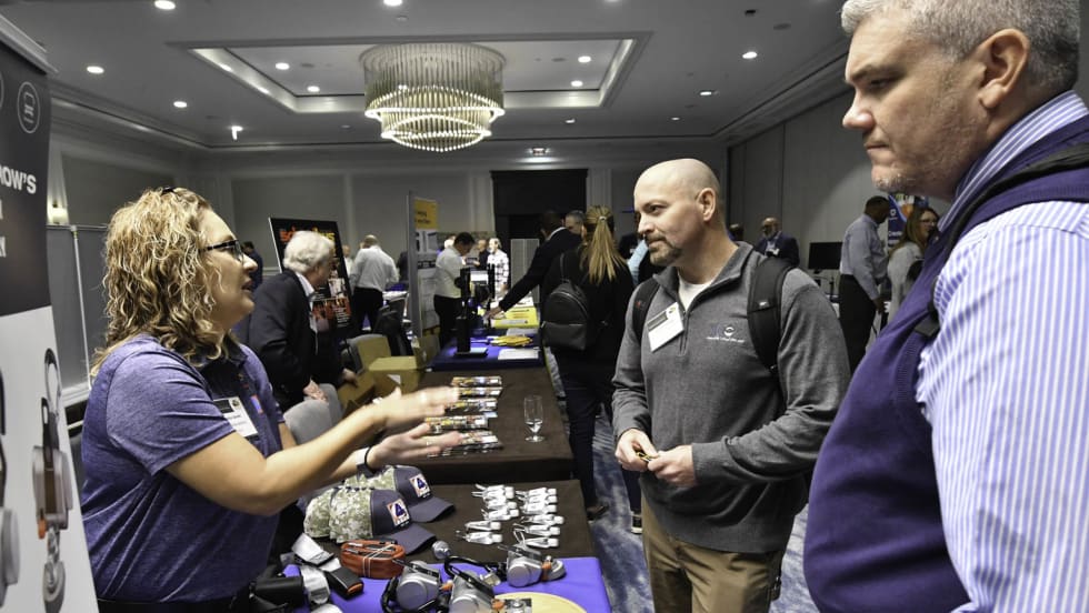trade show attendees talk to each other over a table