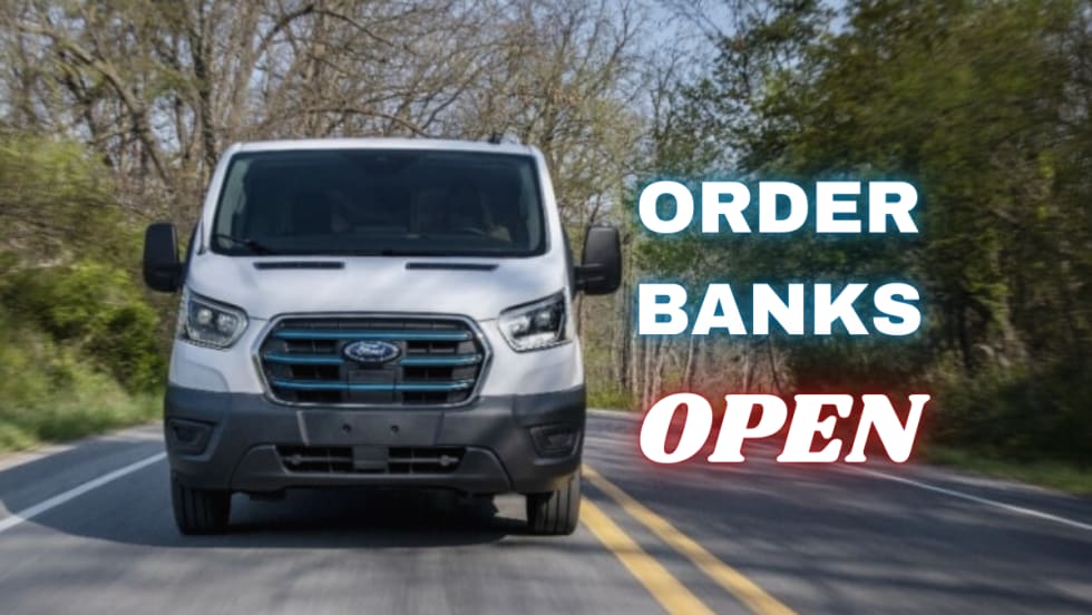 A front view of a Ford E-Transit van driving down a road surrounded by trees. Neon sign text to the right reads "Order Banks Open". 