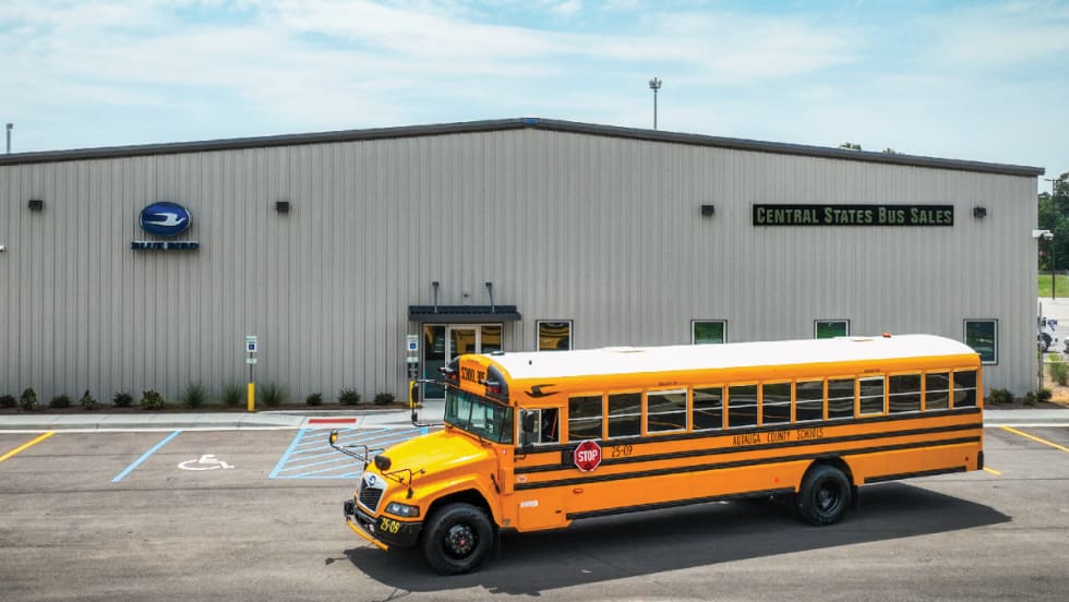 A school bus parked in front of a warehouse building.