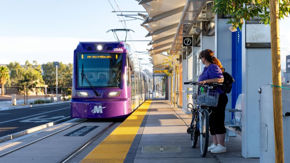 A woman with a bike waits on a rail platform for an incoming train.