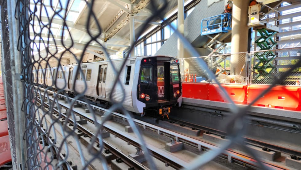 A WMATA train through a chain link fence.