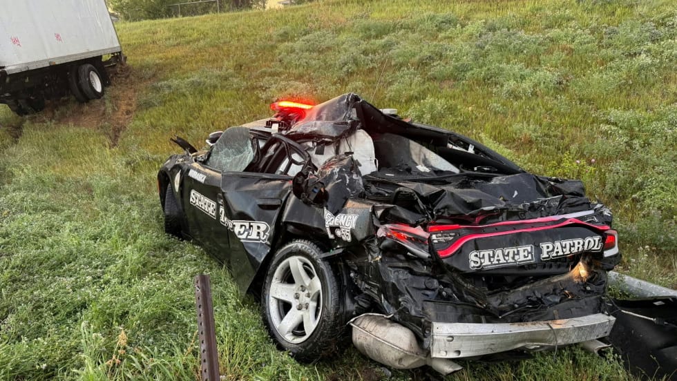 Severely damaged State Patrol police car crashed on grassy roadside