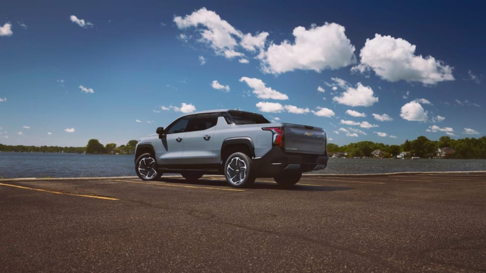 A powder blue 2025 Chevrolet Silverado EV in a parking lot by the water.