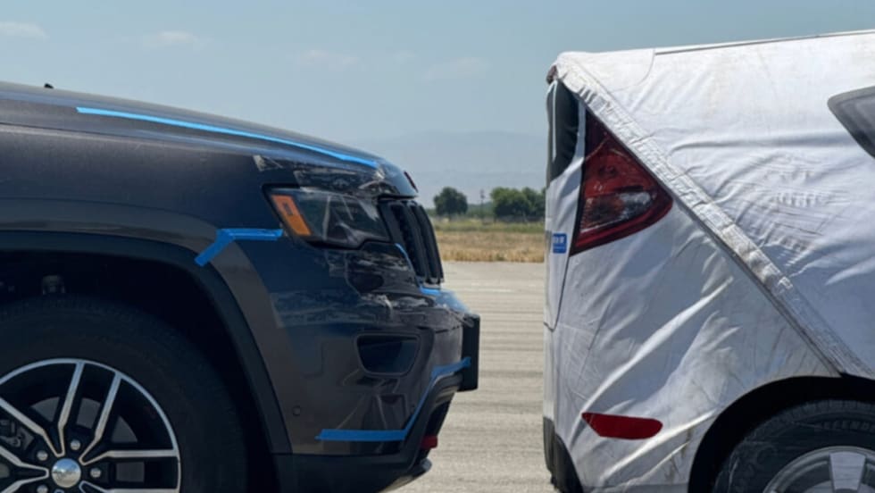 An image of a crash test with a gray car stopping right before hitting a white test car.