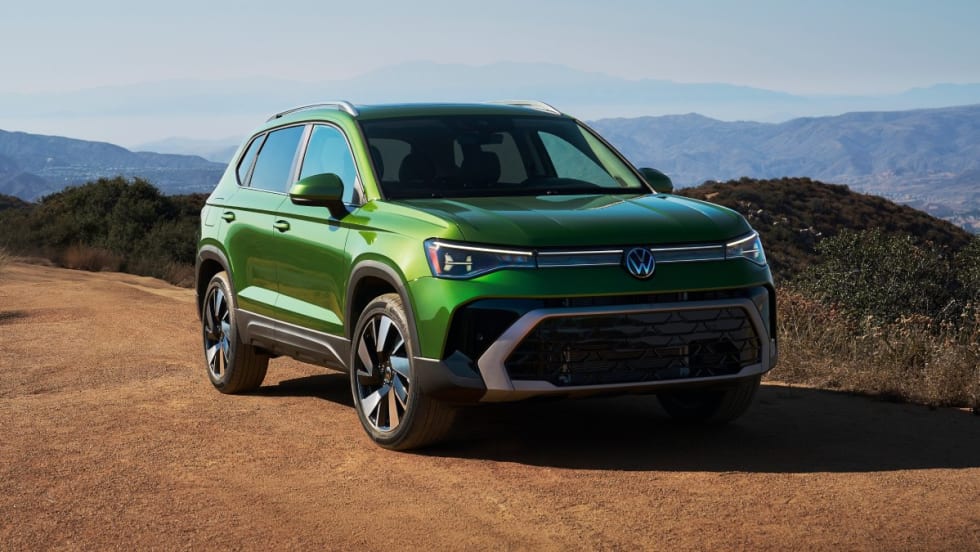 A bright green 2025 Volkswagen Taos parked on a dirt road with mountains in the background.