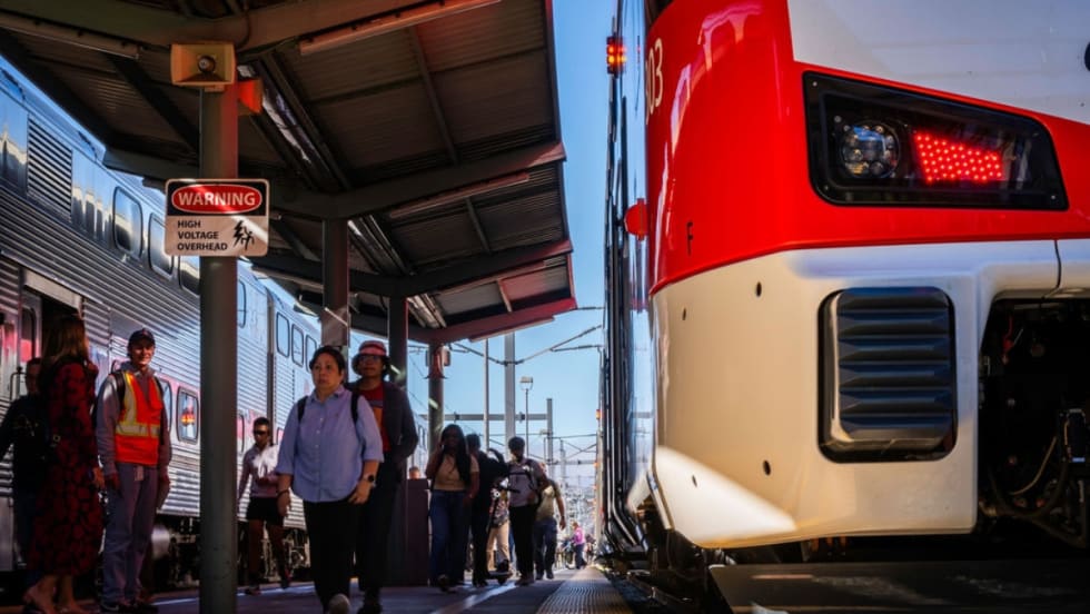Low view of a Caltrain platform with a train parked at it with passengers nearby.