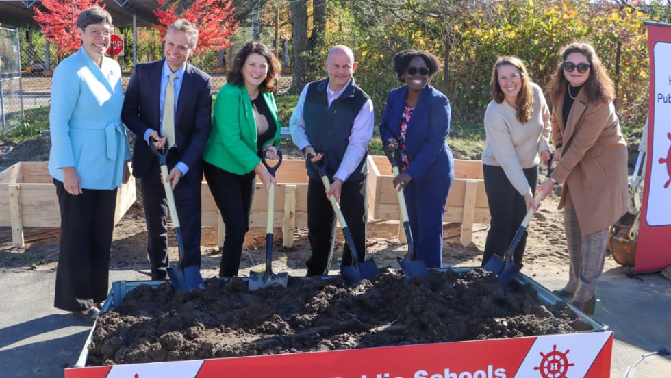 A group of people stand with shovels in dirt.