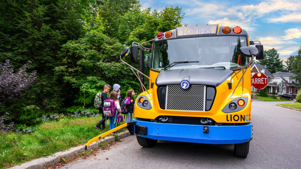 A Canadian LION school bus picks up students at a bus stop.