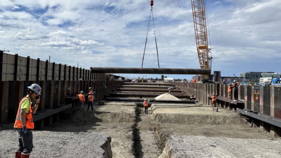 Construction workers guide material hanging from a crane.