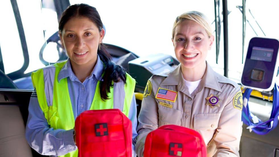 Two female workers hold up NARCAN emergency treatment kits. 