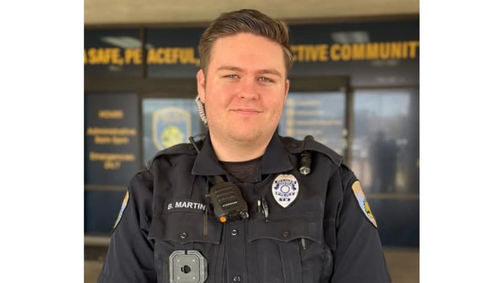Police officer in dark uniform standing in front of community center backdrop