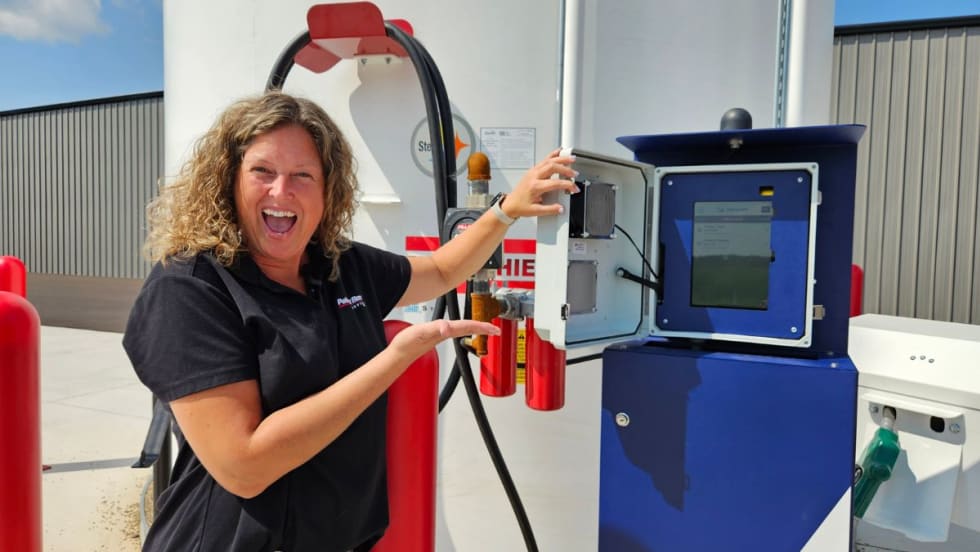 a woman stands in front of fuel tanks
