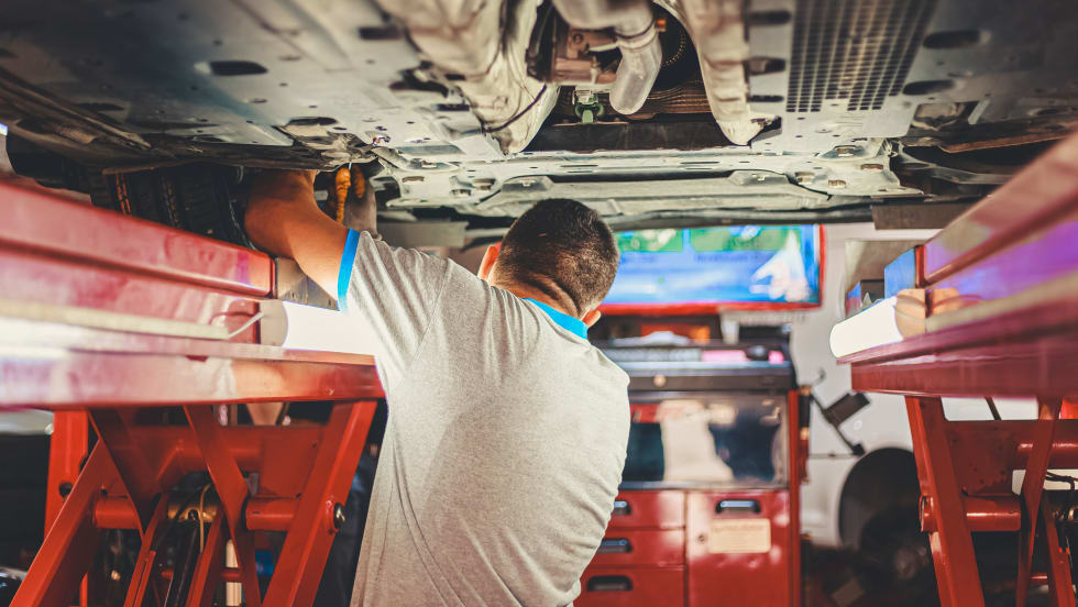 man performing maintenance under a car 