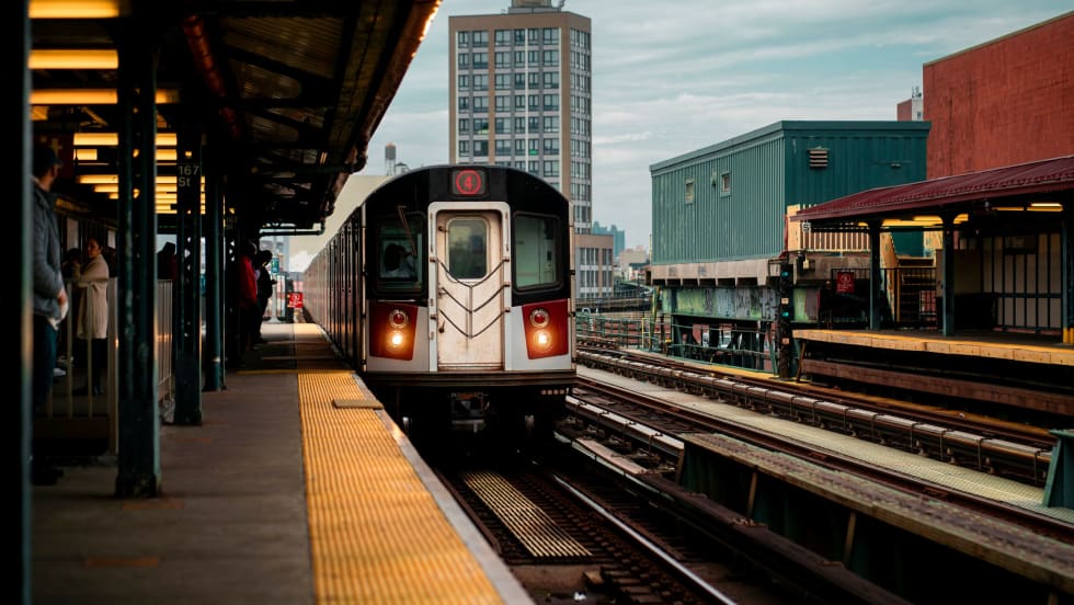 A subway train arriving at a Bronx station in New York City during the day.