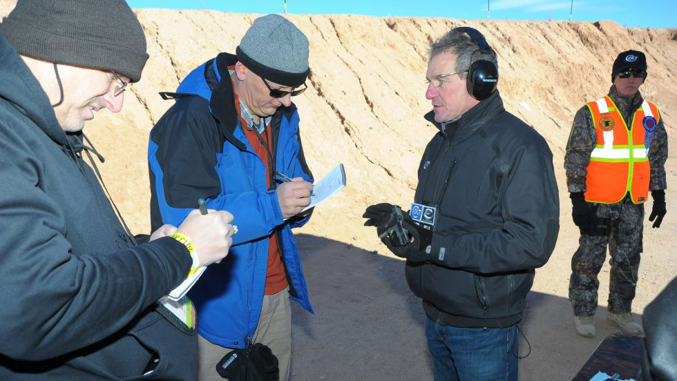 Group of professionals in winter gear examining documents near rocky terrain